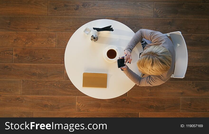 Young business women holding mobile phone text message during rest in coffee shop. Top view