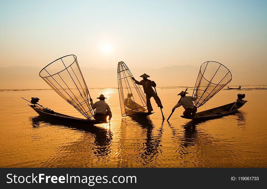 Three Men Riding Boats on Body of Water