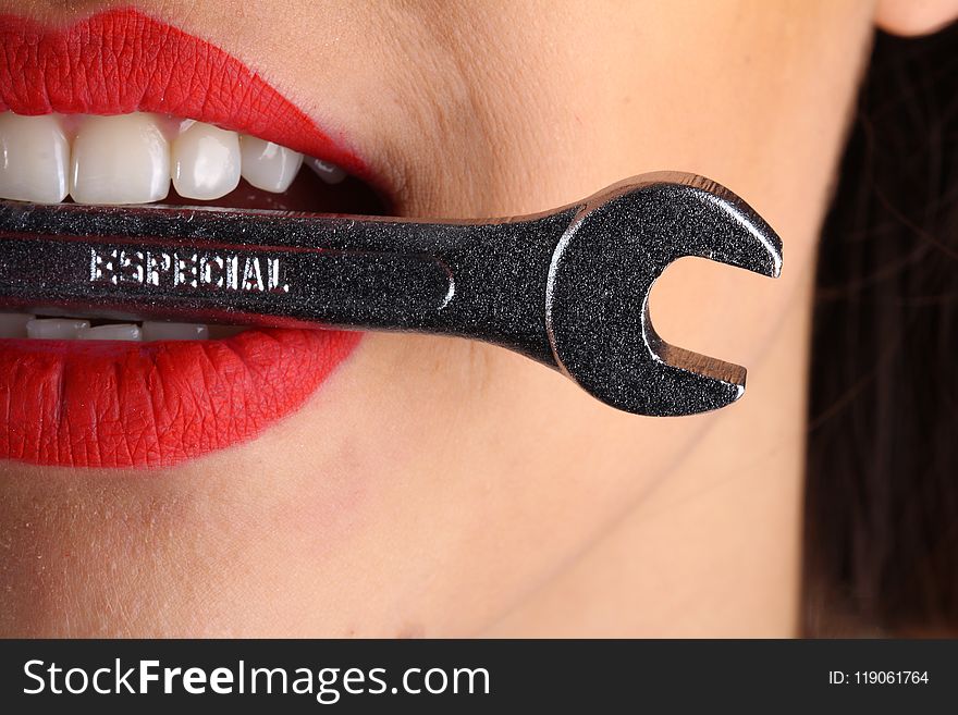 Close View of Woman With Red Lips Biting Gray Special Wrench