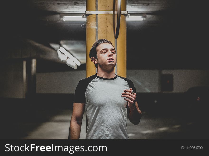 Man Wearing Gray And Black Raglan T-shirt Standing Near Orange Post