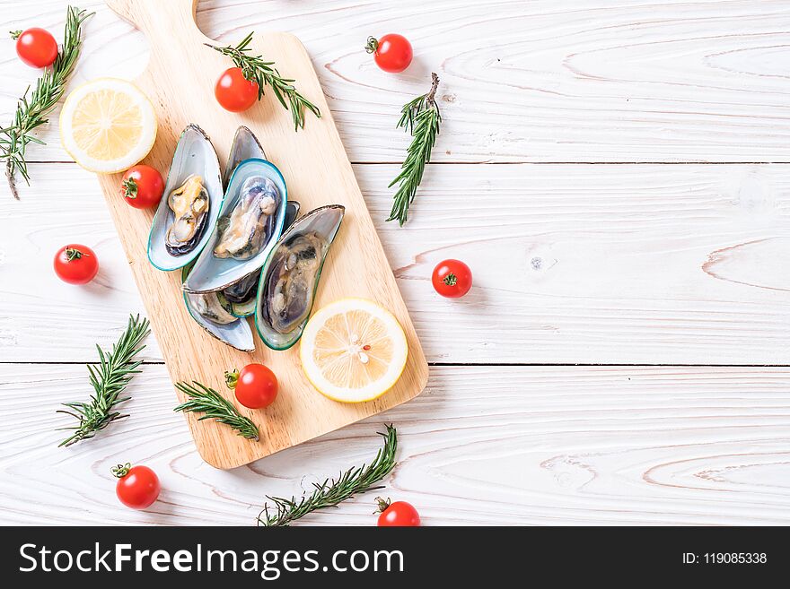fresh mussels on wooden board with ingredients