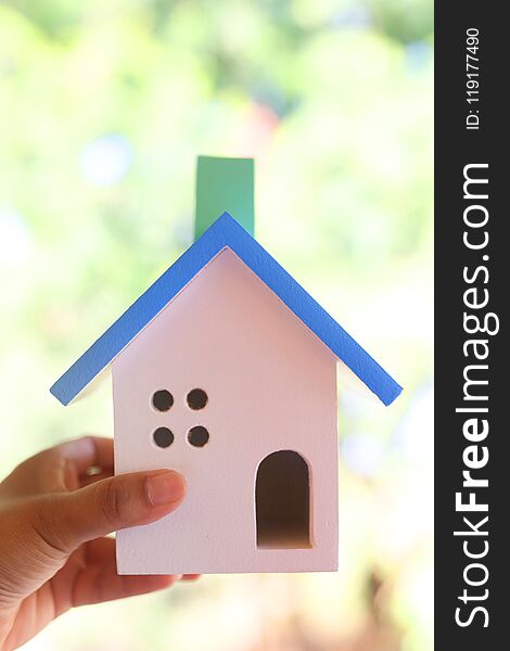 Hand Holding Wooden Toy House Made From Many Pieces. Natural Background