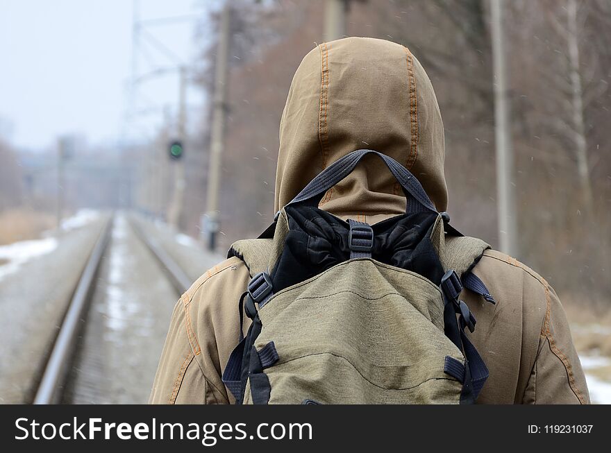 A man with a large backpack goes ahead on the railway track during the winter season .