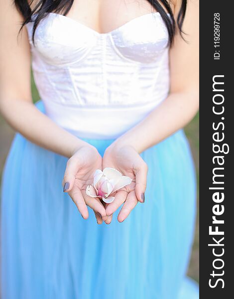 Brunette woman keeping magnolia flower in hands.