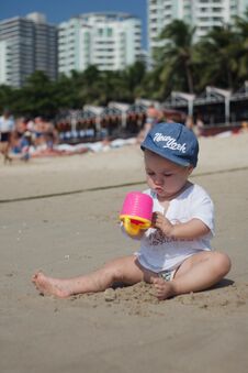 A Child In Sun-protective Clothes And A Headdress Plays On A Sandy Beach On A Clear Hot Day, Vertical Photo. Stock Photography A Child In Sun-protective Clothes And A Headdress Plays On A Sandy Beach On A Clear Hot Day, Vertical Photo. Stock Photography