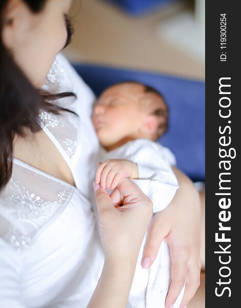 Young Mother Wearing White Clothes Holding Newborn Baby.