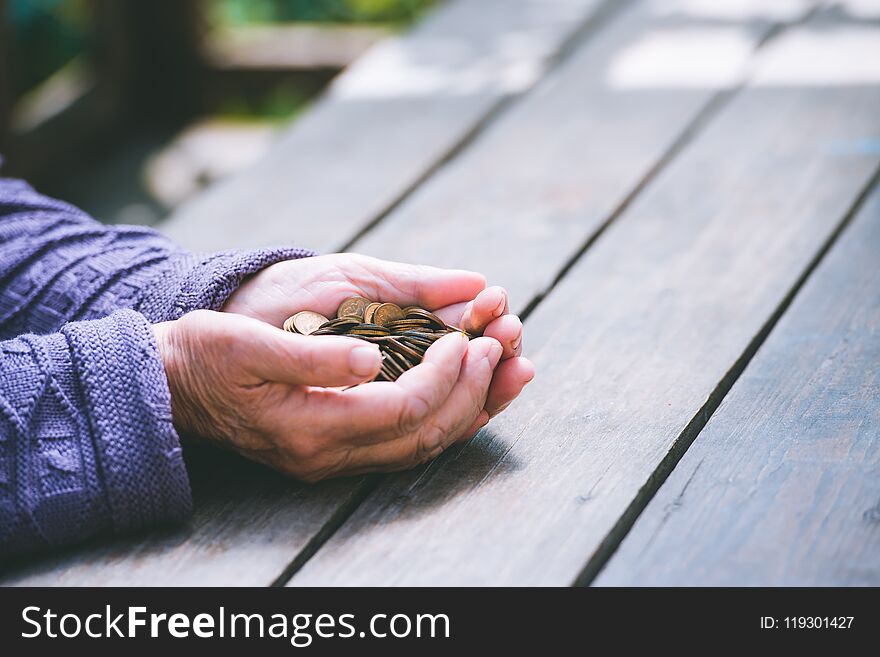 Hands Of The Old Woman Recalculate Coins On A Wooden Table