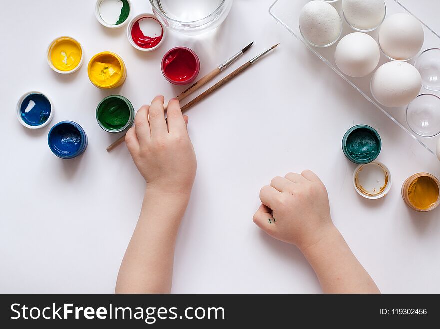 Children`s hands paint Easter eggs. The child is drawing, step by step.