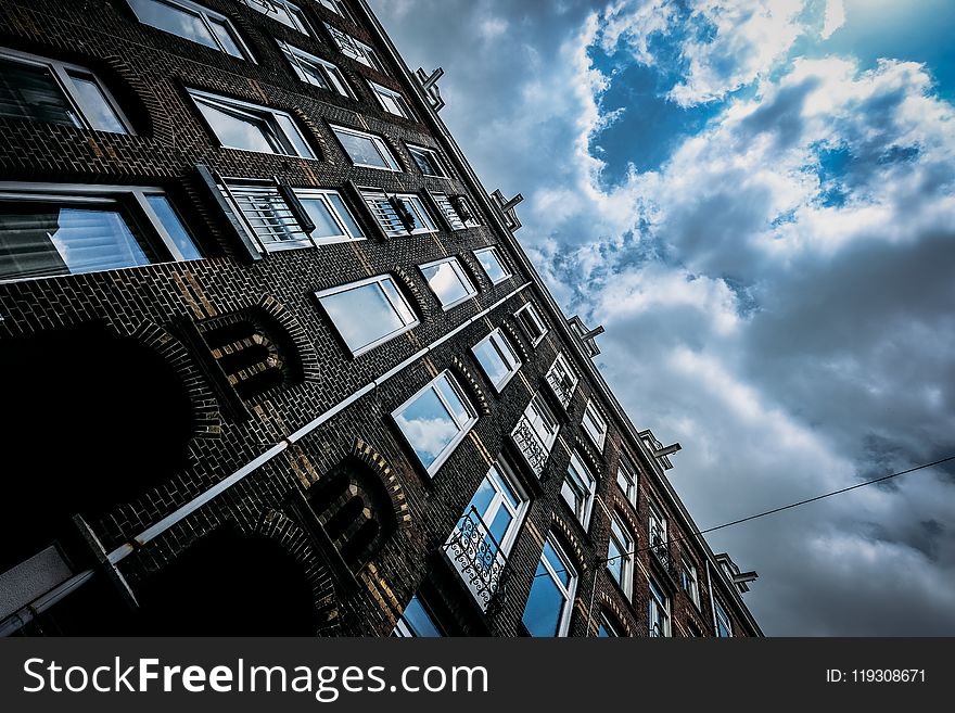 Brown Concrete Building Under Blue and White Cloudy Sky