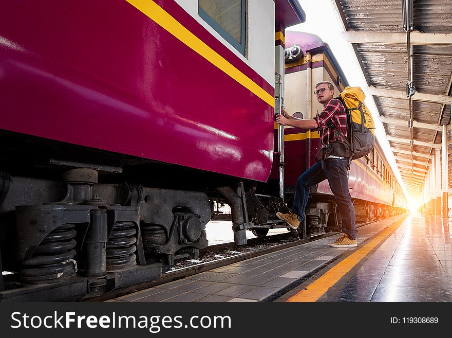 Man With Yellow and Black Backpack Standing Near Train