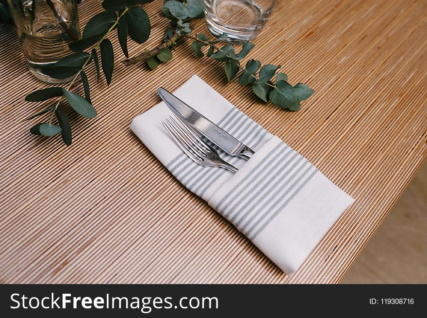 Silver Fork And Knife Inside Gray And White Table Napkin On Table