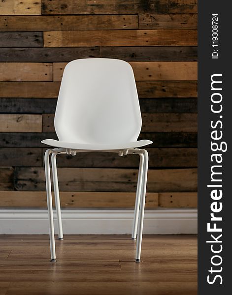 White Plastic Chair Beside Brown Wooden Wall In Home