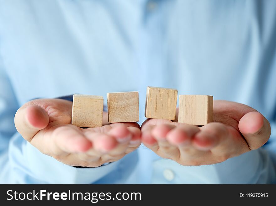 Hand holding four blank wooden cubes, business concept background, mock up, template