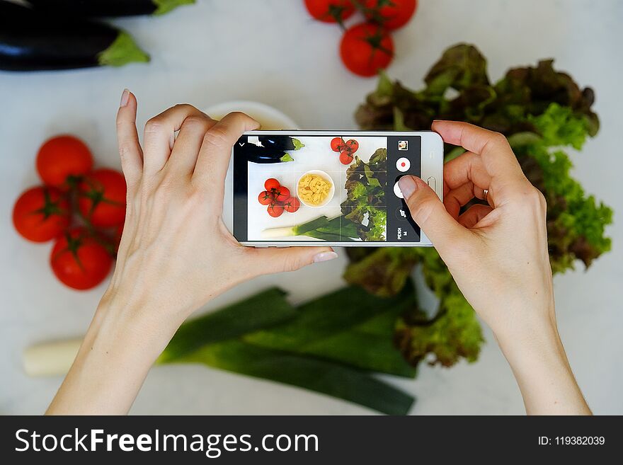Food blogger concept. Hands with the phone close-up pictures of food. Top view.