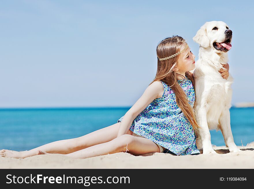 Young girl with her dog by seaside playing on the sand