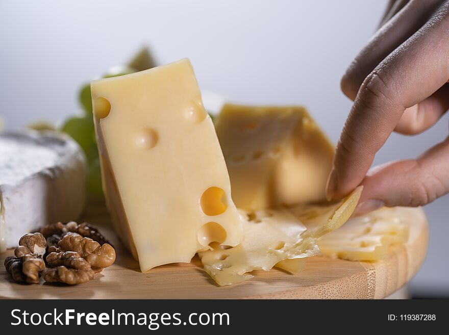 woman takes a piece of Maasdam cheese. On white background