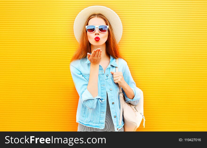 Stylish cool girl sends an air kiss on orange background