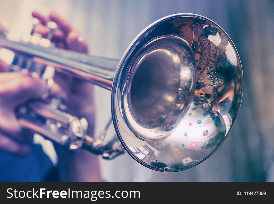 The trumpeter is playing on a silver trumpet. Trumpet player