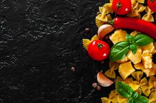 Farfalle Pasta, Red Chili Peppers, Cherry Tomato, Basil, Black Pepper, Garlic, Parmesan Cheese On Dark Background Stock Photography