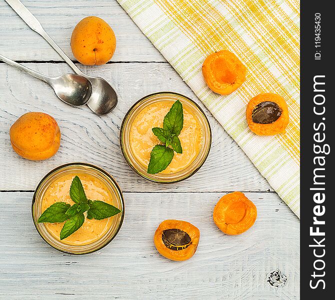 Smoothies of mulberries, apricot and mint in glass jars on white wooden background