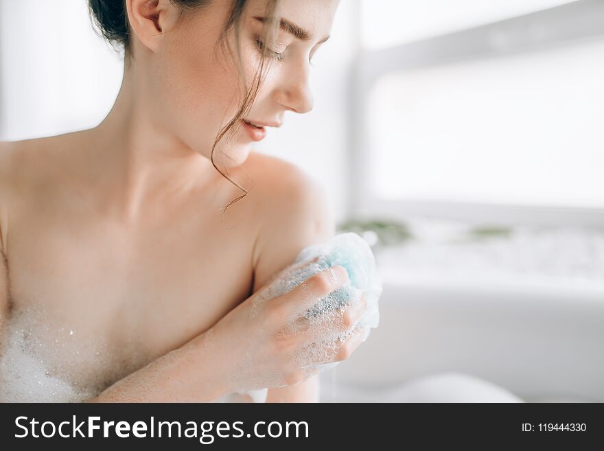 Female person soaps the body with a sponge