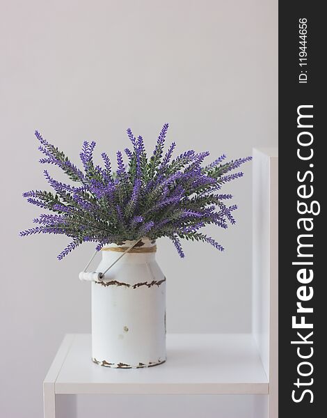 Lavender in a vintage iron pot is on a white wooden shelf. Lavender in a vintage iron pot is on a white wooden shelf