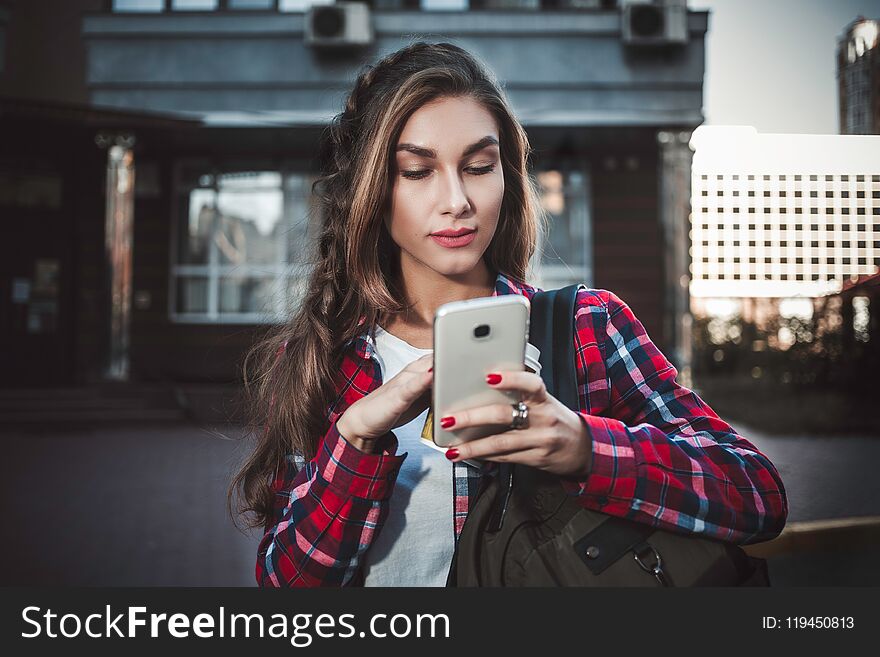 Photo of cute girl walking at street and using a smatphone