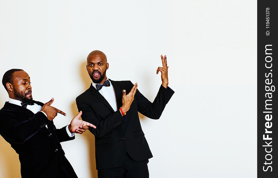 Two afro-american businessmen in black suits emotional posing, gesturing, smiling. wearing bow-ties, lifestyle people concept