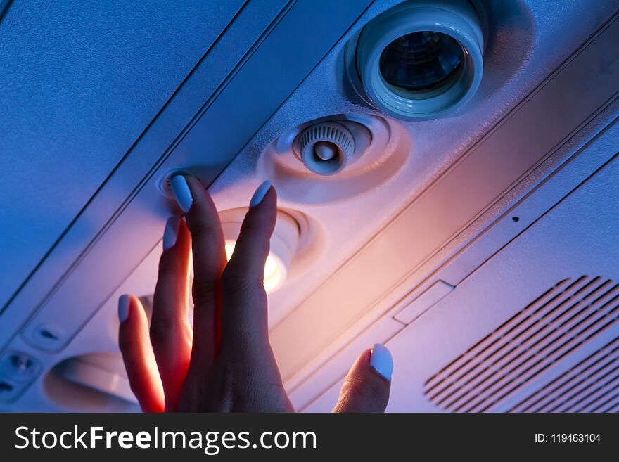 The passanger hand closeup turn on the light in the airplane