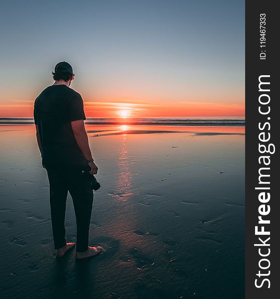 Man Standing on Beach during Sunset