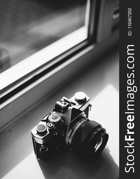 Grayscale Photo Of Classical Camera Near Window