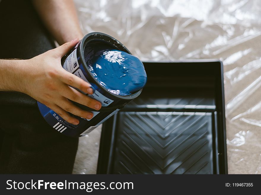 Person Holding Can of Blue Paint