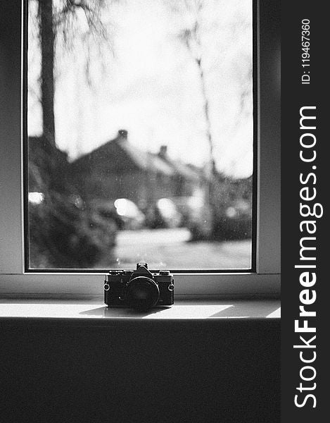 Grayscale Photo Of Camera Beside Window