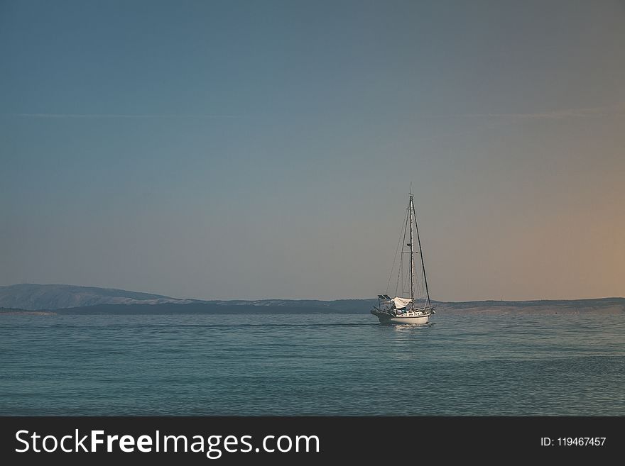 White Sailboat on Body of Water Under White Sky