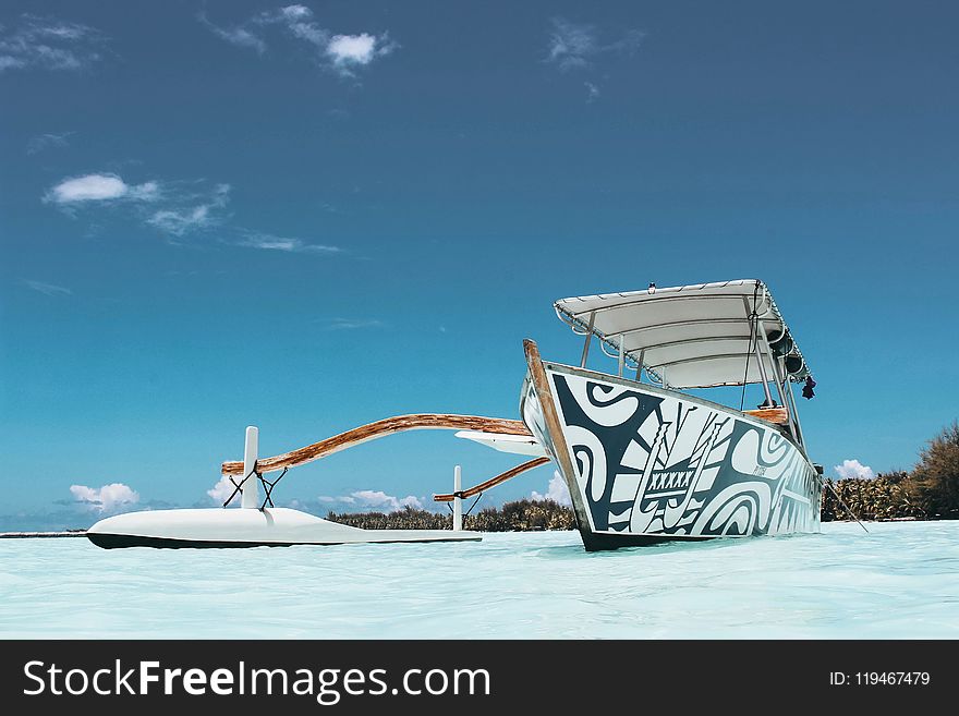 White and Blue Wooden Canoe Under Blue Sky at Daytime