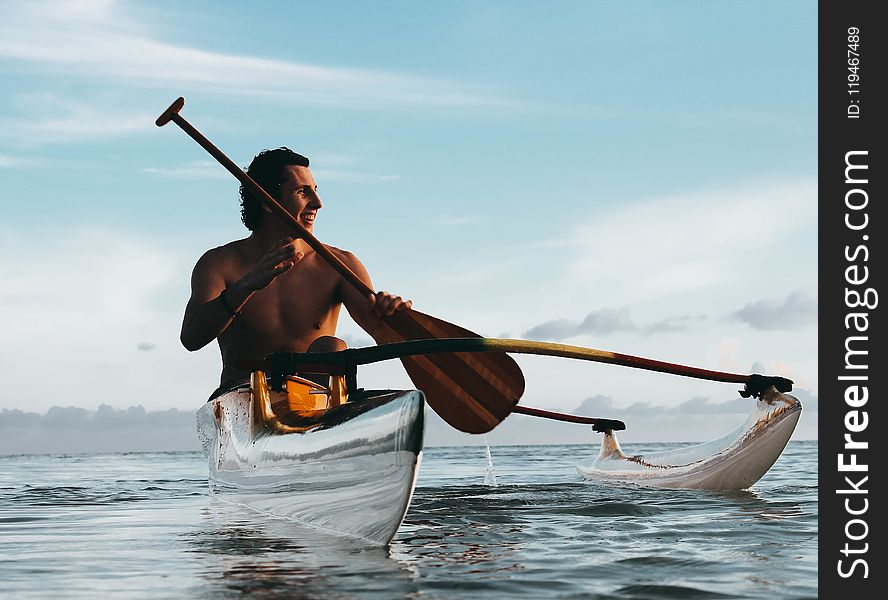 Man Riding On Boat Holding Brown Paddle