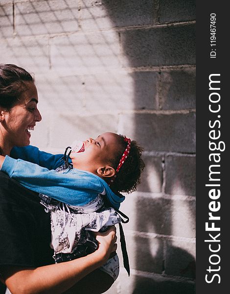 Woman in Black Top Carrying Girl Wearing Blue Hoodie