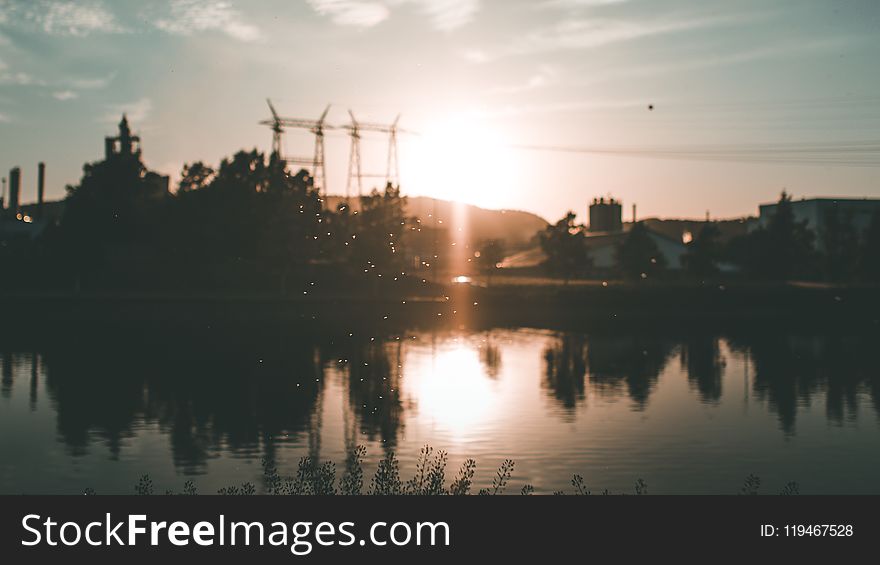 Silhouette of Building and Trees Near Body of Water during Golden Hour