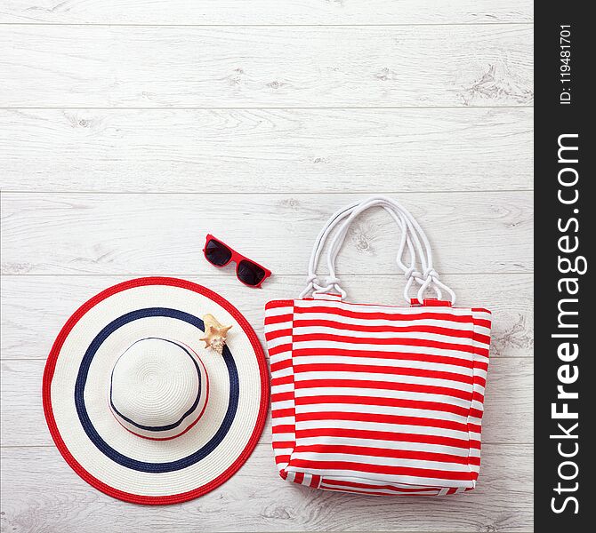 Summer accessories hat and bag on white wooden background.