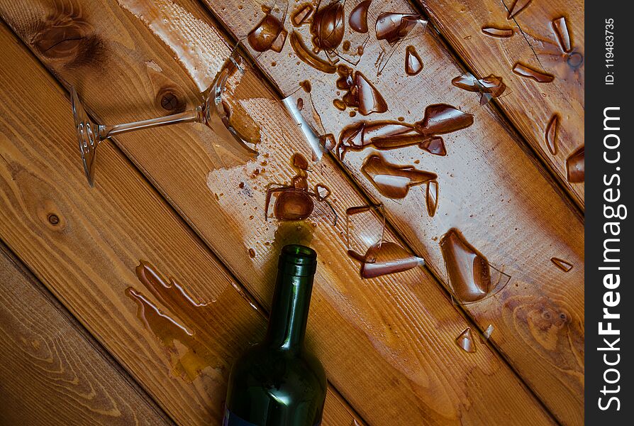 Broken wine glass with bottle on wooden table. Broken wine glass with bottle on wooden table