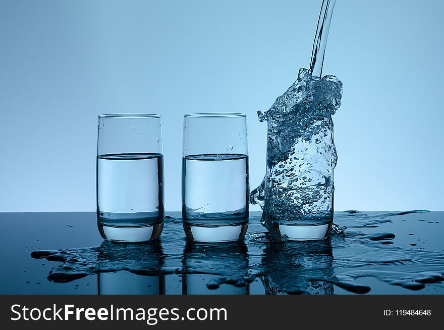 Creative splashing water in the glass on blue background.