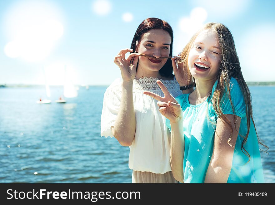 Two beautiful and cheerful girls on the background of the sea and sailing boats. Two beautiful and cheerful girls on the background of the sea and sailing boats.