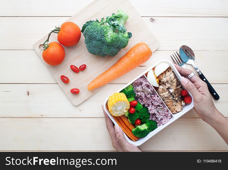 Top view of woman`s hands holding healthy lunch box with chicken