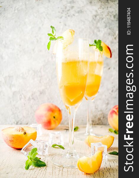 Summer cold alcohol beverage, iced peach Bellini cocktail with mint leaves, light concrete background copy space. Summer cold alcohol beverage, iced peach Bellini cocktail with mint leaves, light concrete background copy space