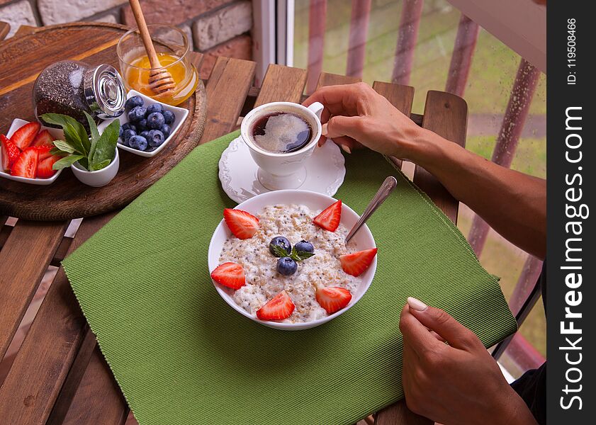 Fitness woman have a breakfast. Healthy Homemade Oatmeal with Berries.