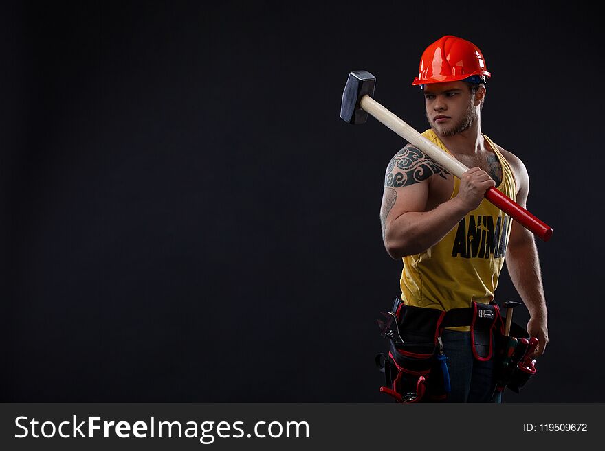 Brutal Muscular worker man with a hammer. man in tattoos on a black background