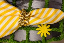 Yellow And White Crisp Linen Napkin With Gold Bee Napkin Ring On A Placemat That Looks Like Paving Stones With Grass- Springtime T Stock Photo Yellow And White Crisp Linen Napkin With Gold Bee Napkin Ring On A Placemat That Looks Like Paving Stones With Grass- Springtime T Stock Photo