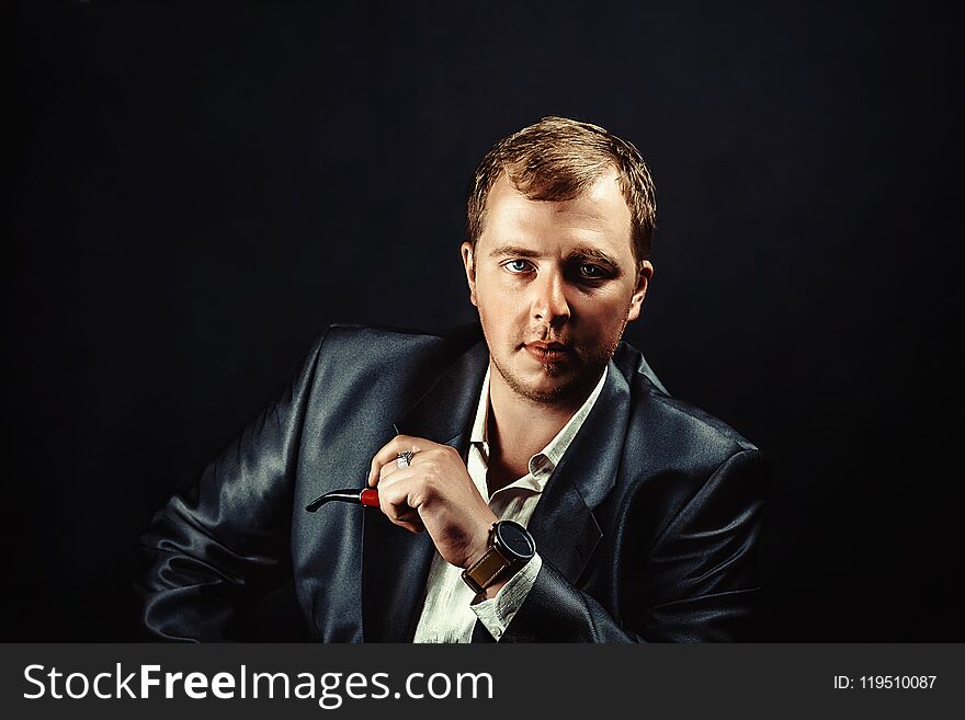 Elegant young man in suit Smoking a pipe. Elegant young man in suit Smoking a pipe