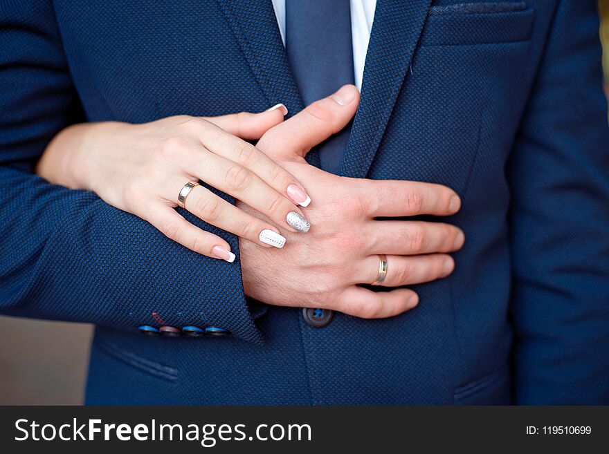 Close-up Bride and groom`s hands with wedding rings. Groom putting golden ring on finger. Love and marriage.