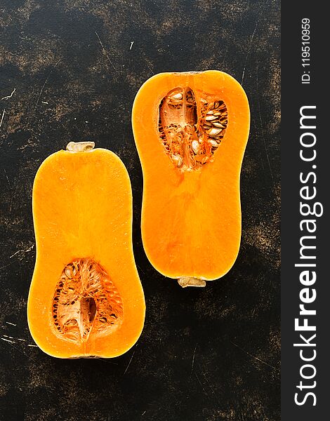 Half A Raw Pumpkin On A Dark Rustic Background. The View From Above, Flat Lay. The Concept Of Autumn.